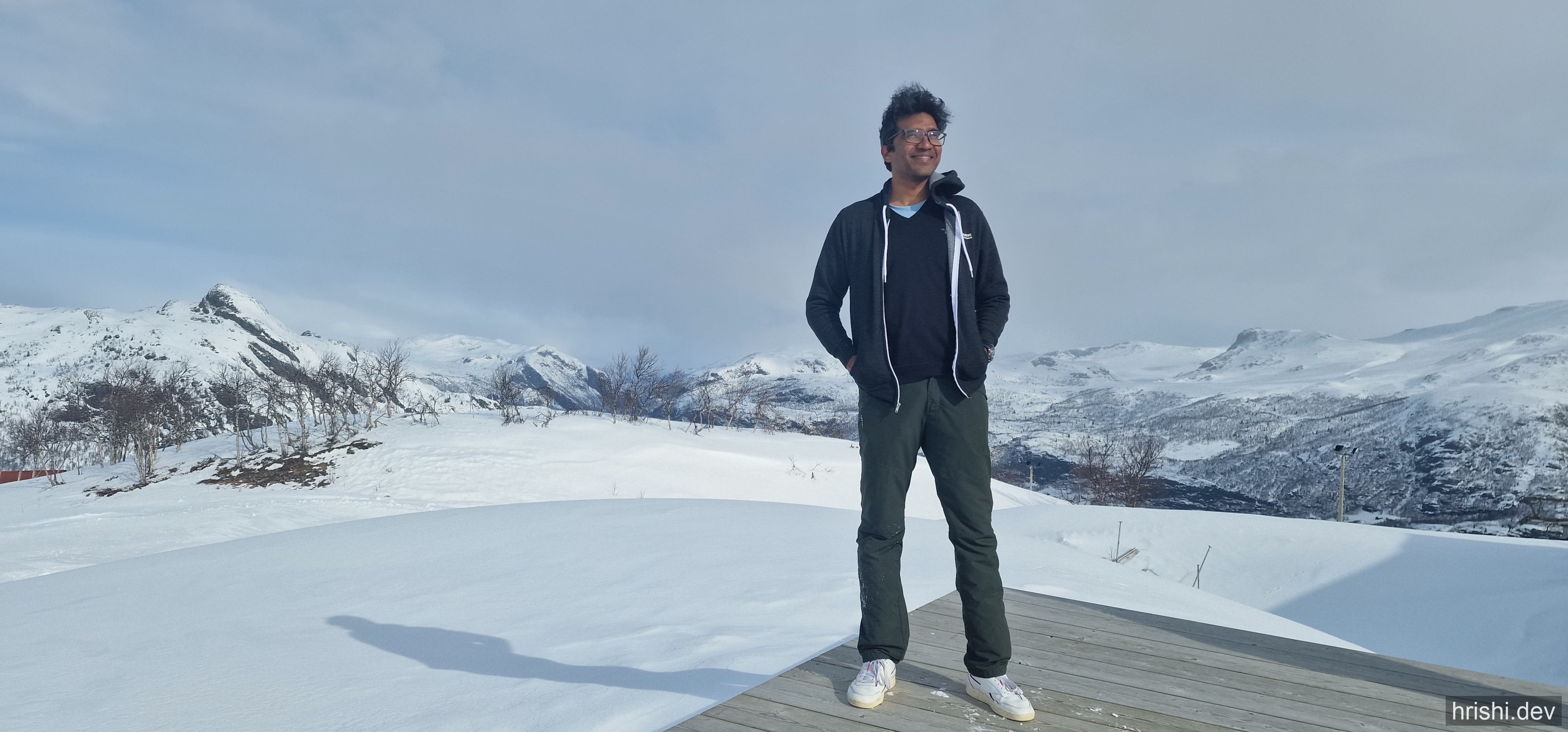 Standing in pajamas and sneakers on a snowy deck in Hemsedal, Norway, with mountains in the background
